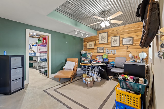 interior space with ceiling fan, concrete flooring, and wood walls