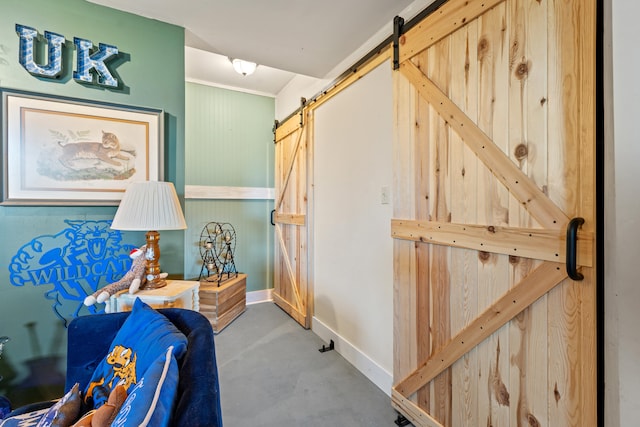 hall with finished concrete floors, baseboards, and a barn door