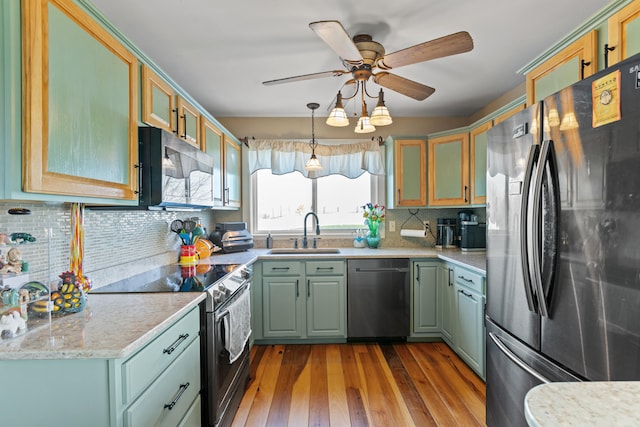 kitchen with backsplash, glass insert cabinets, appliances with stainless steel finishes, hardwood / wood-style flooring, and a sink