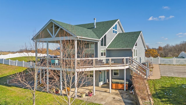 rear view of property featuring stairway, a wooden deck, roof with shingles, a sunroom, and a patio area