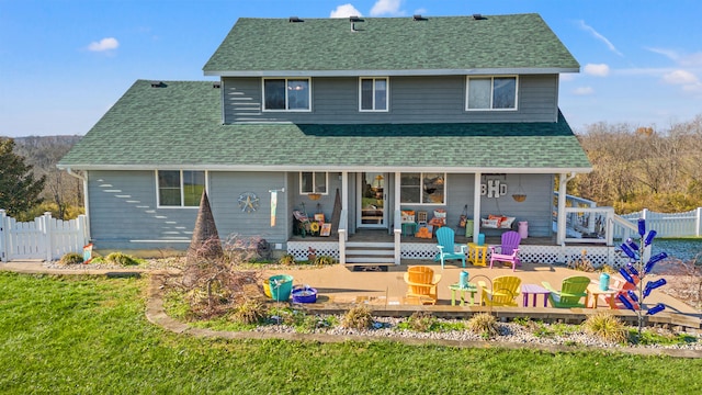 rear view of property with a porch, a shingled roof, a yard, and fence