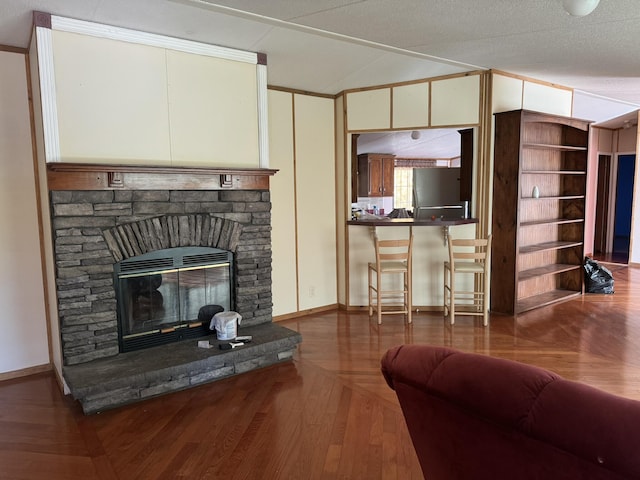 living room with crown molding, a stone fireplace, parquet flooring, and a textured ceiling