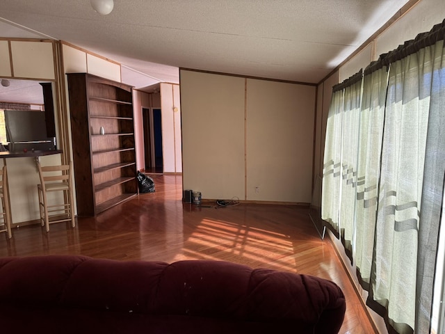 bedroom with wood-type flooring, a textured ceiling, and ornamental molding