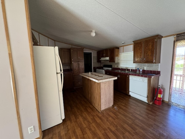 kitchen featuring white appliances, tile countertops, a center island, dark hardwood / wood-style floors, and lofted ceiling