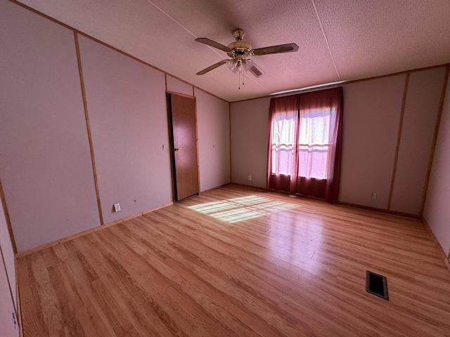 unfurnished room with a textured ceiling, light hardwood / wood-style floors, and ceiling fan