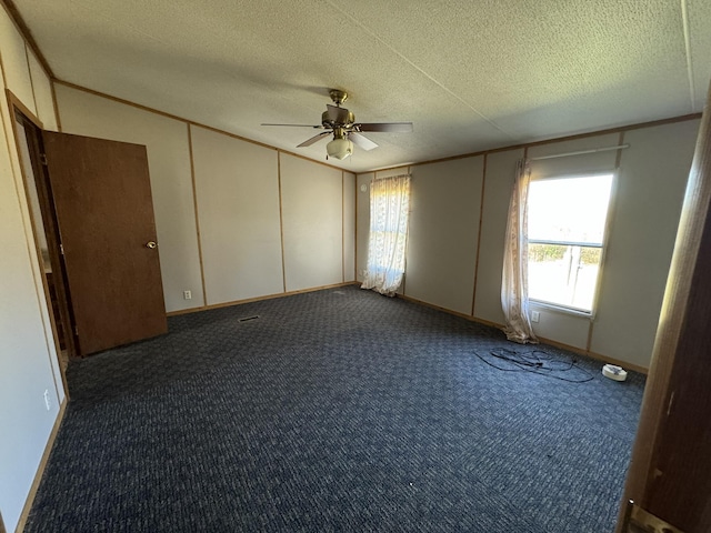 unfurnished bedroom featuring dark colored carpet, a textured ceiling, and ceiling fan