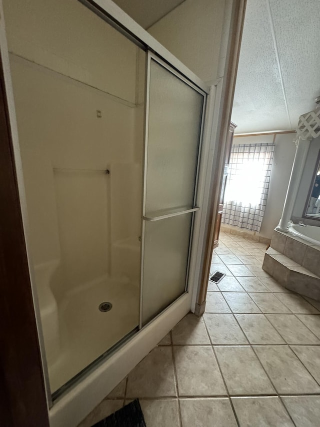 bathroom with tile patterned flooring, shower with separate bathtub, and a textured ceiling