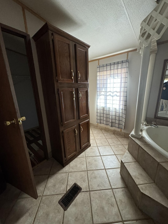 bathroom with tile patterned flooring, a textured ceiling, a tub to relax in, and ornamental molding