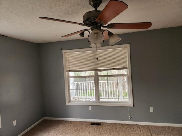 carpeted empty room featuring ceiling fan and a textured ceiling