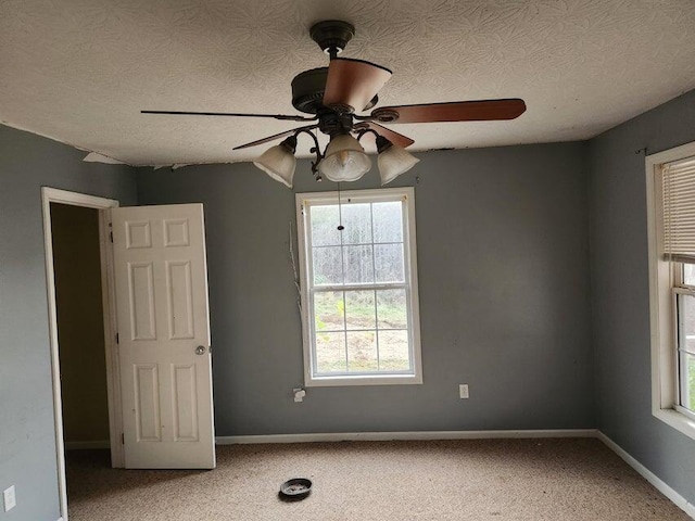 empty room featuring carpet flooring, plenty of natural light, ceiling fan, and a textured ceiling