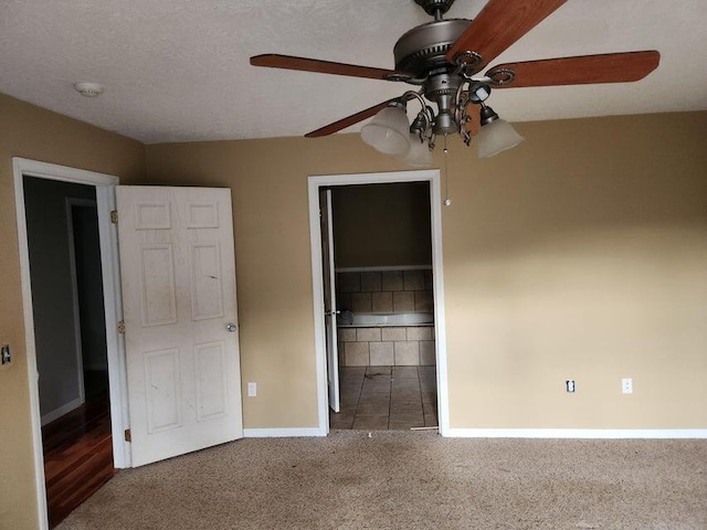 unfurnished bedroom featuring carpet, a walk in closet, a textured ceiling, ceiling fan, and a closet