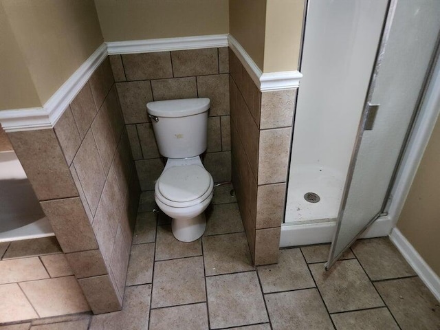 bathroom featuring a shower, tile walls, and toilet