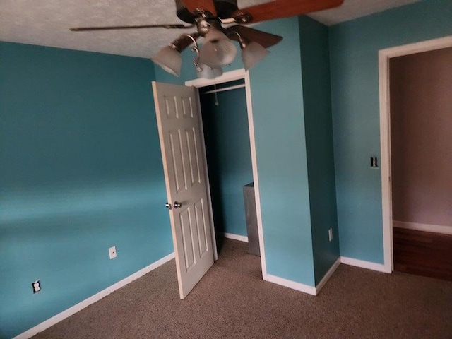 unfurnished bedroom with dark colored carpet, ceiling fan, and a closet