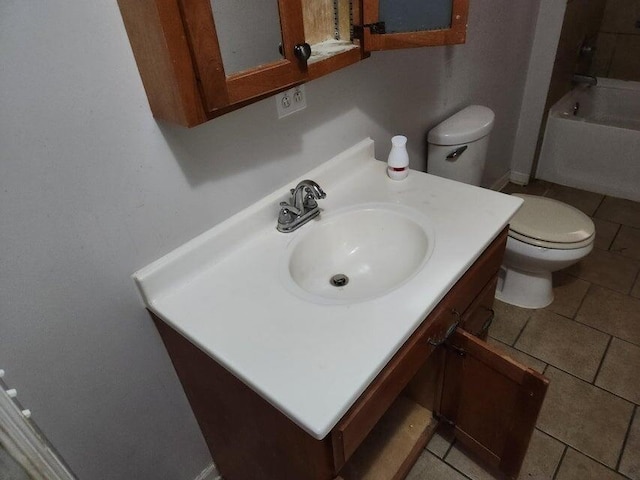 bathroom with a washtub, vanity, and toilet