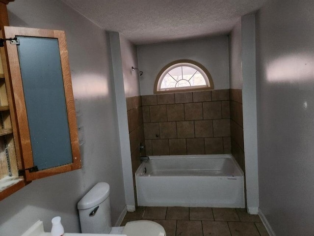 bathroom featuring a tub, tile patterned flooring, a textured ceiling, and toilet