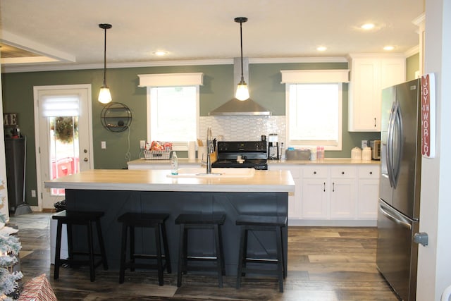 kitchen with hardwood / wood-style floors, a kitchen island with sink, black range oven, white cabinetry, and stainless steel refrigerator