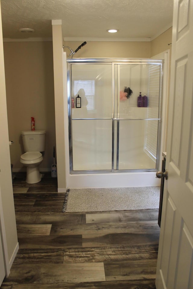 bathroom featuring toilet, a shower with door, and hardwood / wood-style flooring