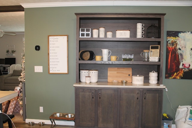 bar featuring dark brown cabinets, ceiling fan, ornamental molding, and a textured ceiling