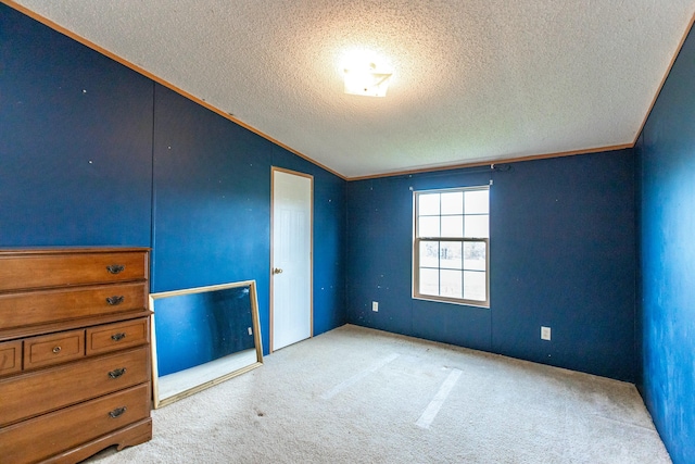 carpeted empty room featuring vaulted ceiling, crown molding, and a textured ceiling