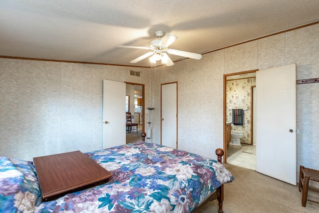 carpeted bedroom with a textured ceiling, ensuite bath, ceiling fan, and crown molding