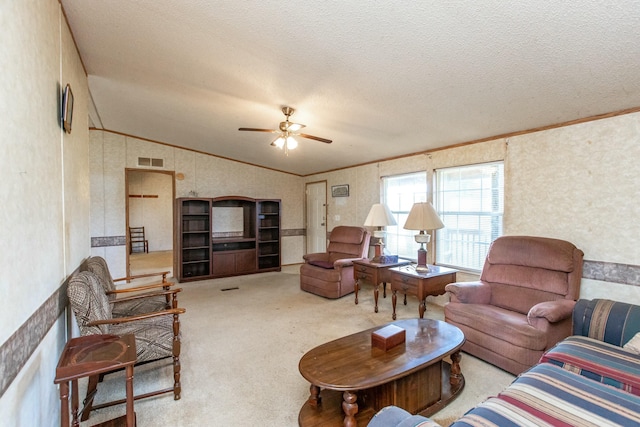 living room featuring lofted ceiling, ceiling fan, ornamental molding, a textured ceiling, and light colored carpet