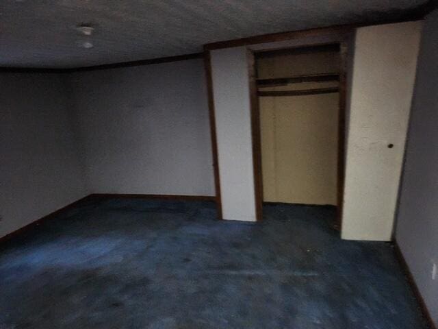 unfurnished bedroom with dark carpet and a textured ceiling