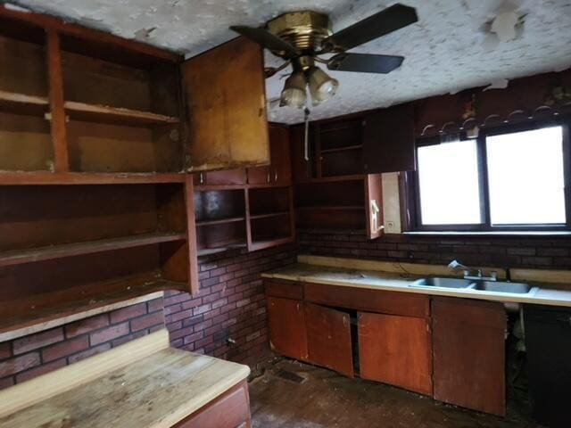 kitchen featuring brick wall, ceiling fan, and sink