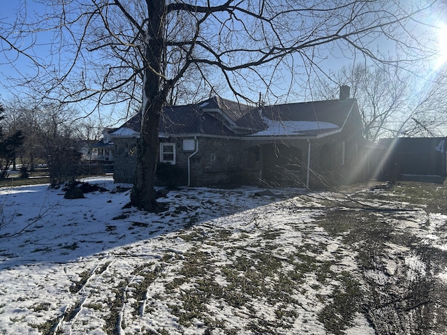 exterior space featuring stone siding and a chimney