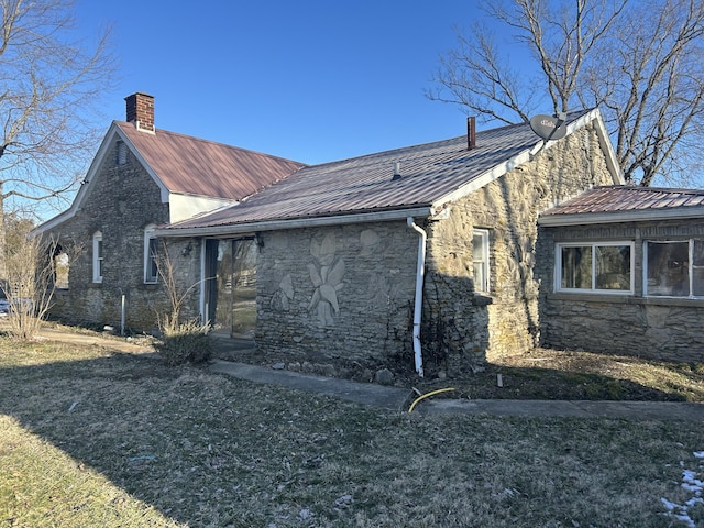 view of property exterior with stone siding, a chimney, and metal roof