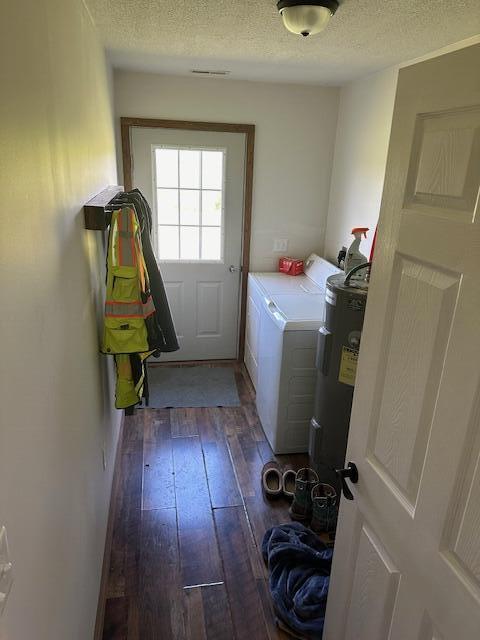 washroom with washer and dryer, dark hardwood / wood-style flooring, electric water heater, and a textured ceiling