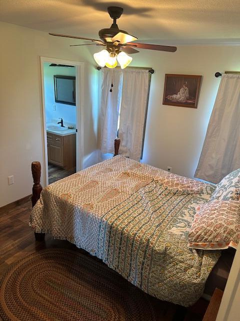 bedroom with ceiling fan, sink, dark wood-type flooring, and connected bathroom