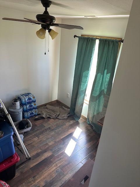 empty room with dark hardwood / wood-style floors and ceiling fan