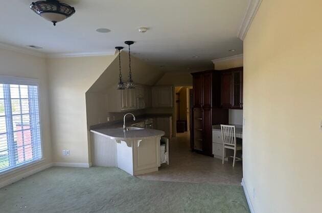 kitchen with crown molding, sink, hanging light fixtures, a kitchen bar, and kitchen peninsula