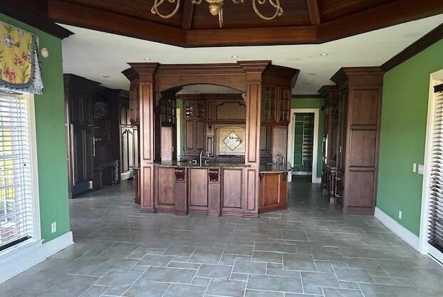 kitchen featuring decorative columns, sink, ornamental molding, and an inviting chandelier