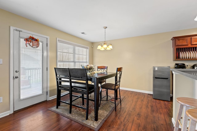 dining room with dark hardwood / wood-style floors and a notable chandelier