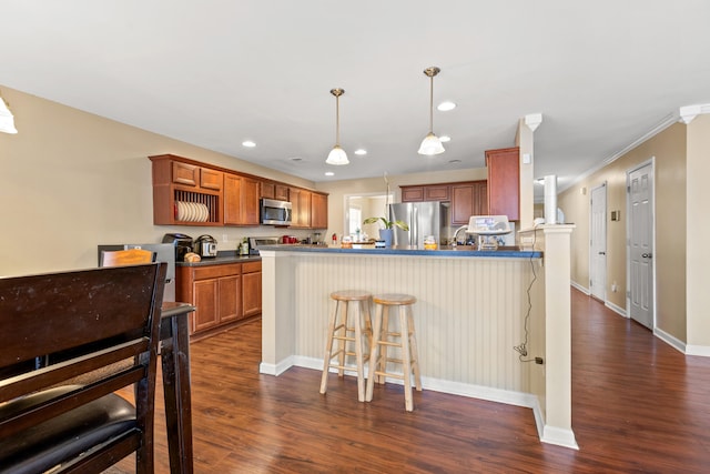 kitchen with a kitchen breakfast bar, stainless steel appliances, crown molding, dark wood-type flooring, and pendant lighting