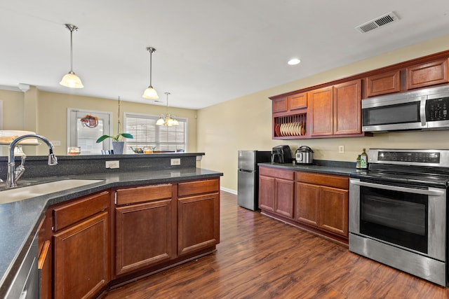 kitchen featuring pendant lighting, sink, appliances with stainless steel finishes, dark hardwood / wood-style flooring, and a chandelier