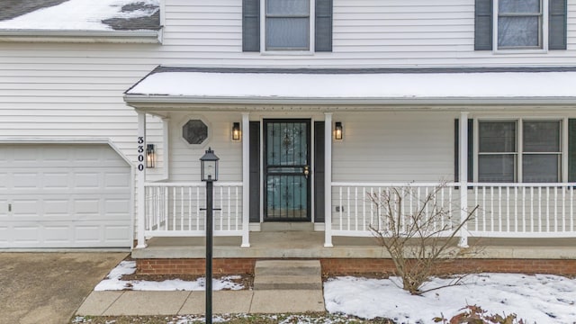 snow covered property entrance featuring a garage