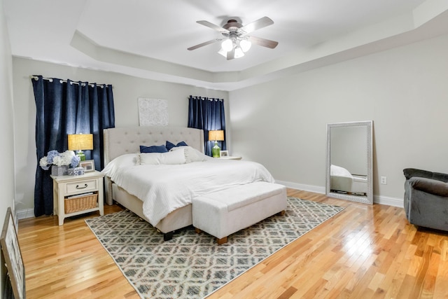 bedroom featuring hardwood / wood-style floors, ceiling fan, and a tray ceiling