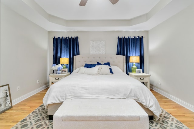 bedroom featuring hardwood / wood-style floors, a raised ceiling, and ceiling fan