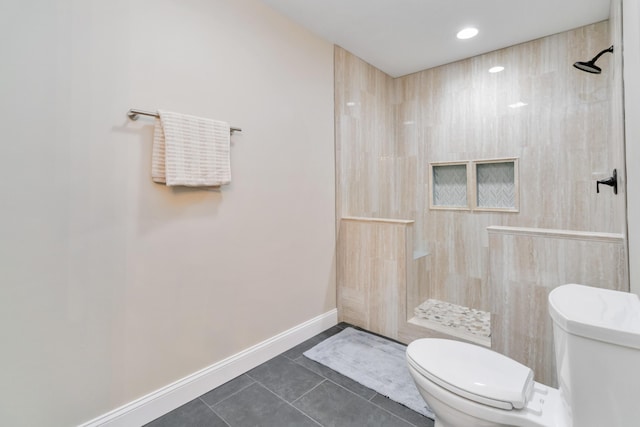 bathroom with tile patterned flooring, toilet, and a tile shower