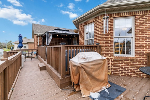 wooden deck with a gazebo and a grill