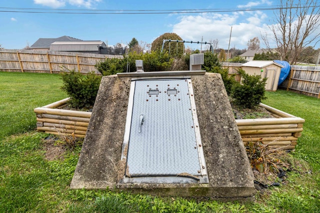 entry to storm shelter with a shed and a yard