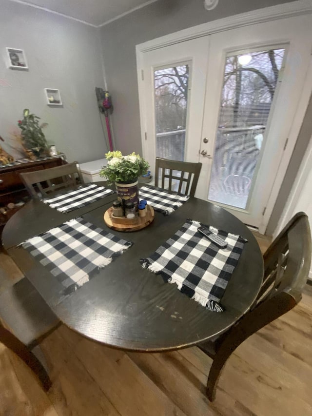 dining space featuring wood-type flooring, french doors, and crown molding