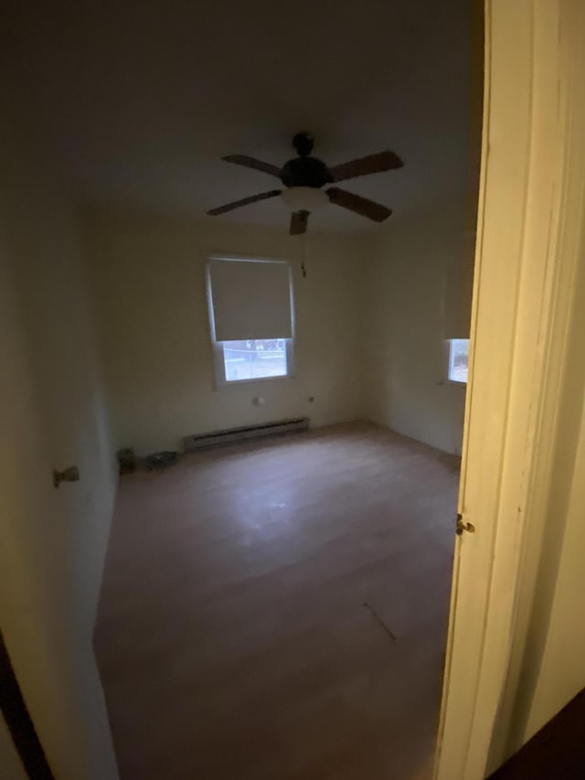 unfurnished room with ceiling fan and a baseboard heating unit