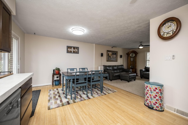 dining room with light wood-style floors, a textured ceiling, visible vents, and a wealth of natural light