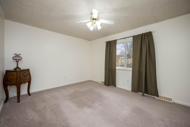 carpeted empty room featuring visible vents, ceiling fan, and a textured ceiling