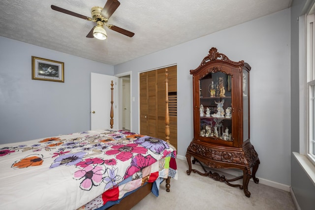 carpeted bedroom featuring ceiling fan, a textured ceiling, baseboards, and a closet