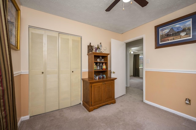 bedroom featuring light carpet, baseboards, a ceiling fan, a textured ceiling, and a closet