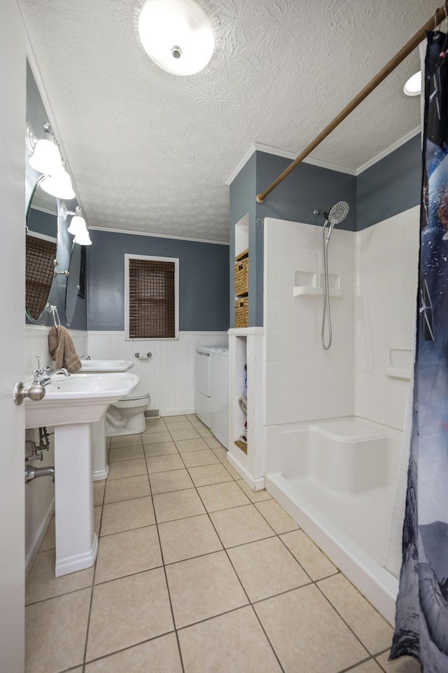 full bathroom with a stall shower, washing machine and dryer, wainscoting, a textured ceiling, and tile patterned floors